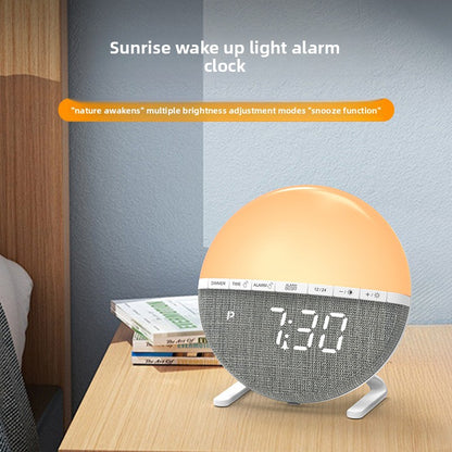 Circular sunrise alarm clock glowing orange and yellow on a minimalist bedside table.
